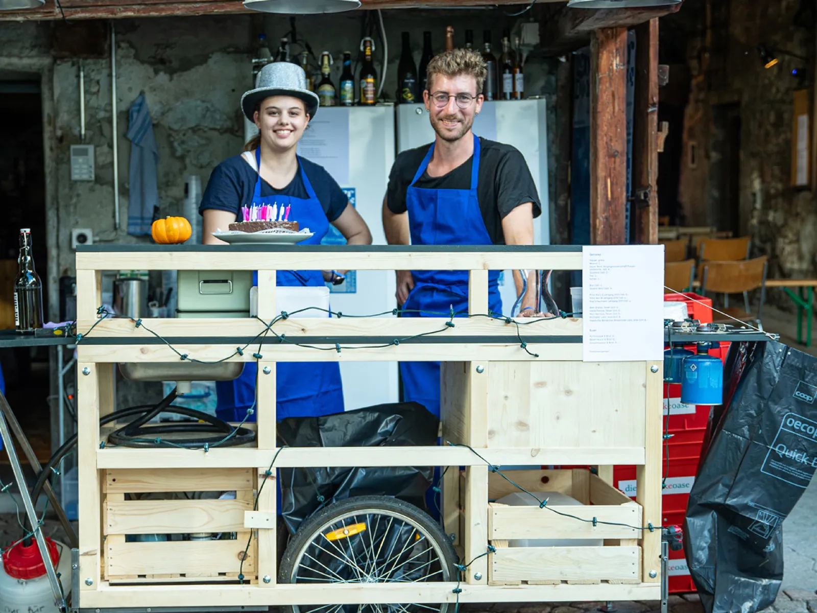 Zwei junge Menschen vor einer selbstgebauten Bar aus Holz