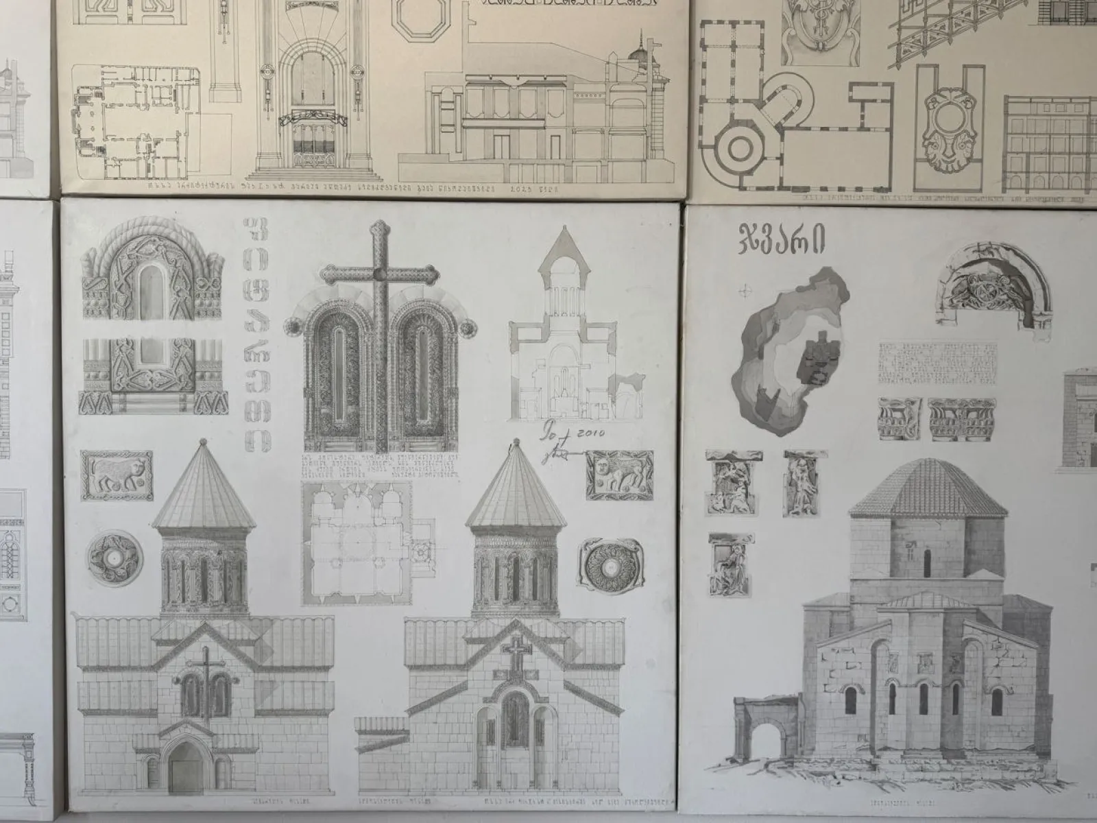 Architekturzeichnungen historischer georgischer Gebäude mit detaillierten Ansichten von Fassaden, Grundrissen und dekorativen Elementen.