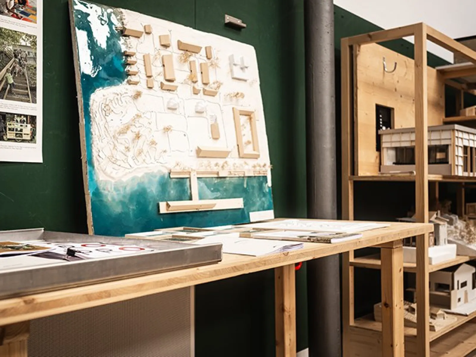 Ein Architekturmodell auf einem Holztisch in einem Studio der Universität Liechtenstein. Im Hintergrund sind weitere Modelle und Materialien zu sehen.