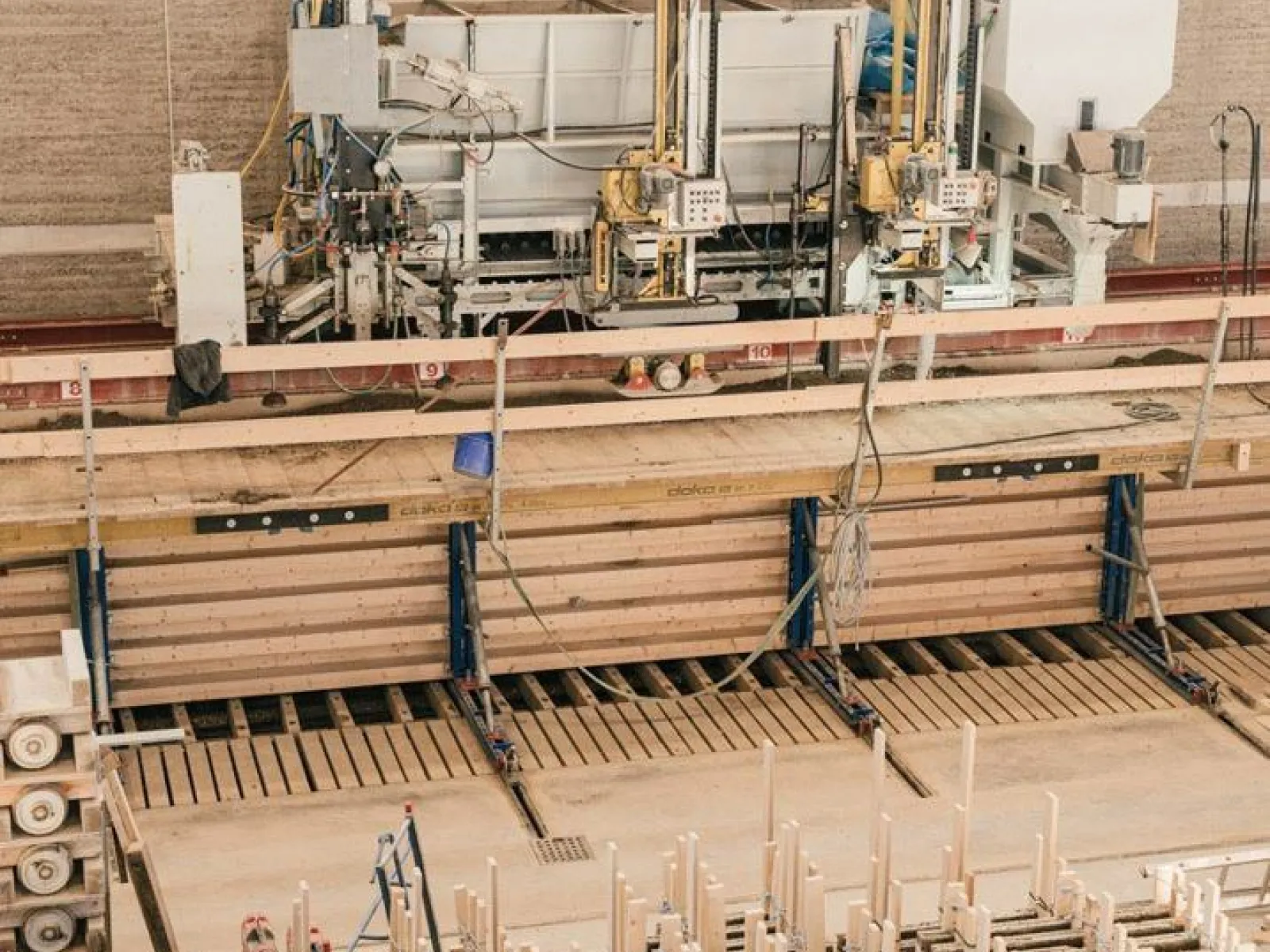 Produktionshalle für Lehmbau mit Maschinen und Holzstrukturen, die den Bauprozess veranschaulichen.