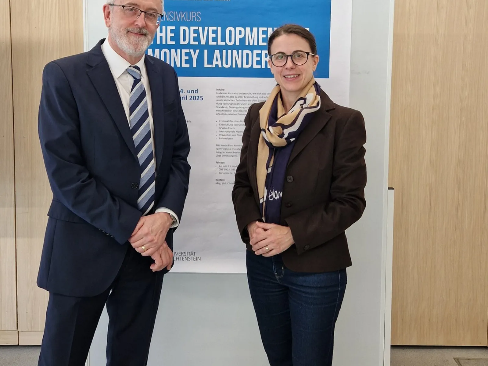 Zwei Personen stehen vor einem Poster des Intensivkurses „The Development of Money Laundering“ an der Universität Liechtenstein.