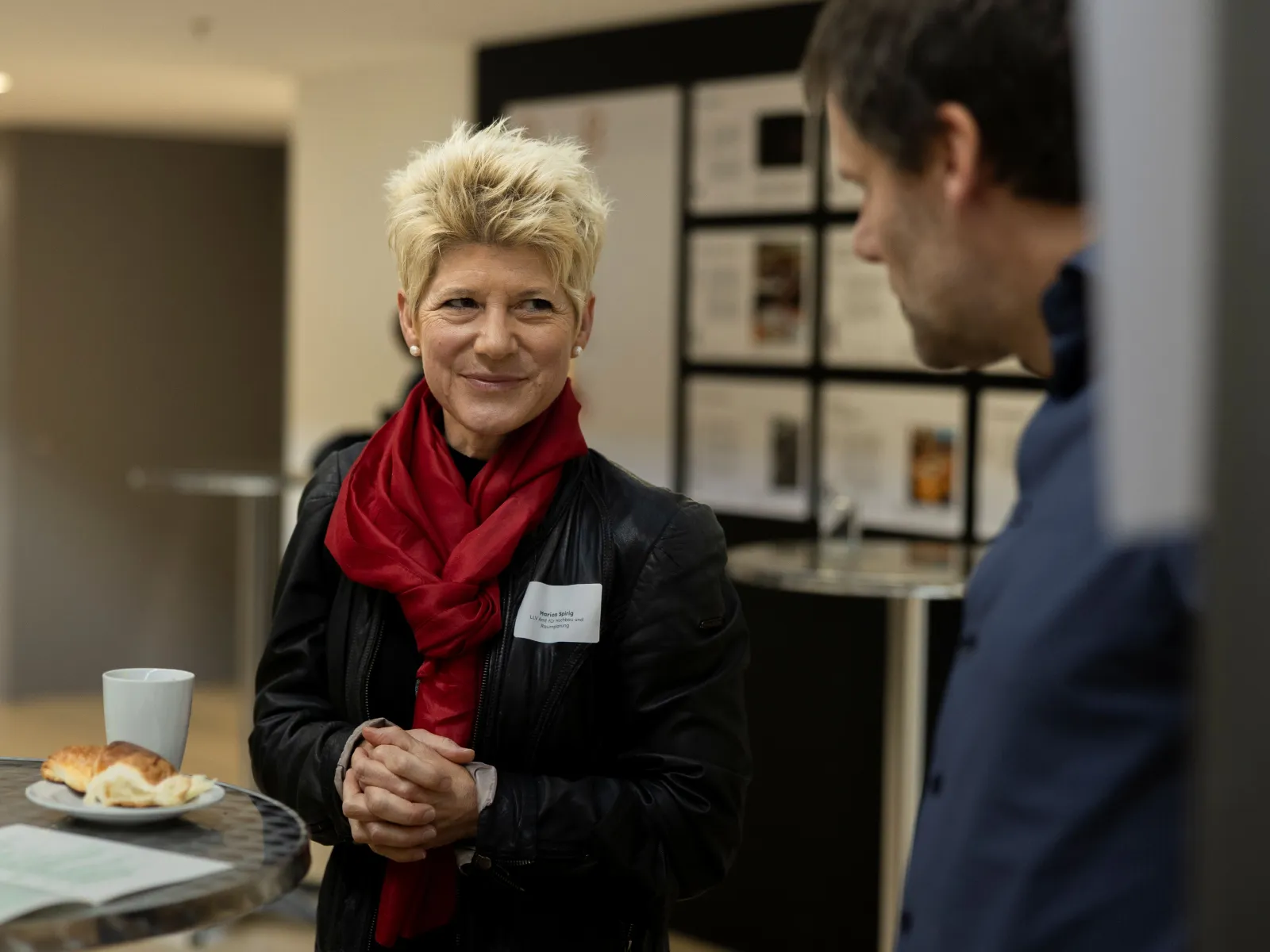 Frau mit kurzen, blonden Haaren und rotem Schal