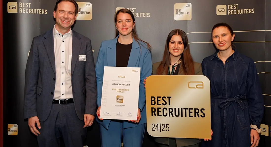 Vier Personen stehen vor einem Hintergrund mit dem Logo "Best Recruiters". Eine Person hält ein Zertifikat mit der Aufschrift "Branchen­sieger Best Recruiter 2024/25". Eine andere Person hält ein Schild mit dem gleichen Logo. Alle lächeln in die Kamera.