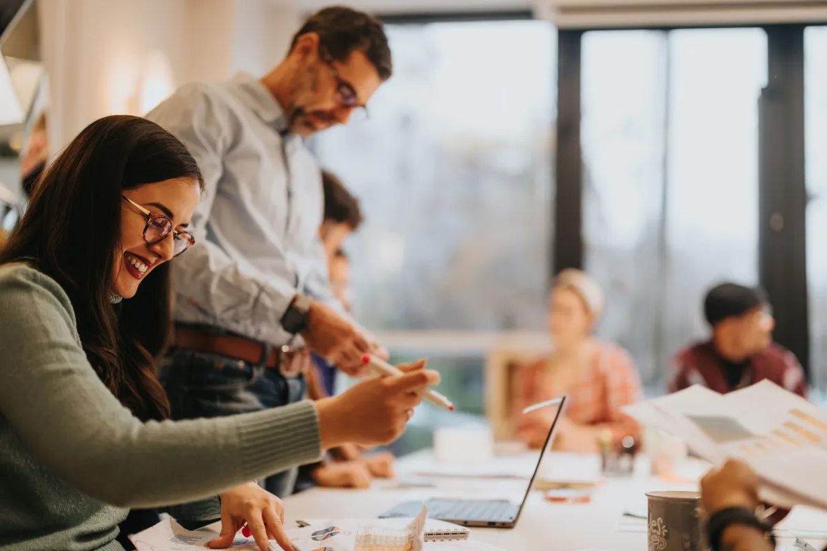 Eine Gruppe von Personen an einem Tisch, die mit Laptops arbeiten, zeigt eine produktive und kooperative Arbeitsatmosphäre, die den Fokus auf Innovation und Digitalisierung widerspiegelt.