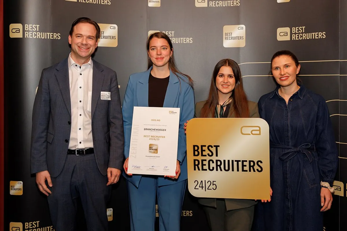 Vier Personen stehen vor einem Hintergrund mit dem Logo "Best Recruiters". Eine Person hält ein Zertifikat mit der Aufschrift "Branchen­sieger Best Recruiter 2024/25". Eine andere Person hält ein Schild mit dem gleichen Logo. Alle lächeln in die Kamera.