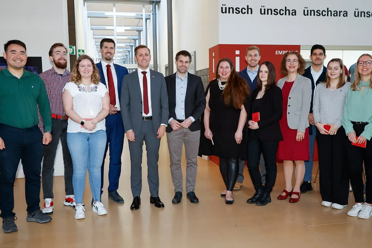 Gruppenfoto von Studierenden und Mitarbeitenden der Universität Liechtenstein mit US-Botschafter Scott C. Miller während seines Besuchs. Die Personen stehen in einem modernen Innenbereich der Universität.