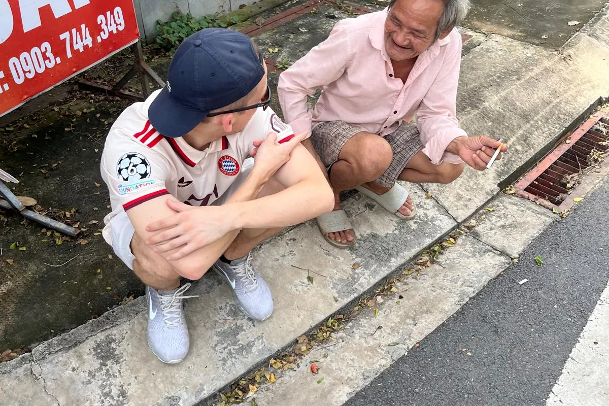 Der Autor zusammen mit einem Vietnamesen am Strassenrand sitzend