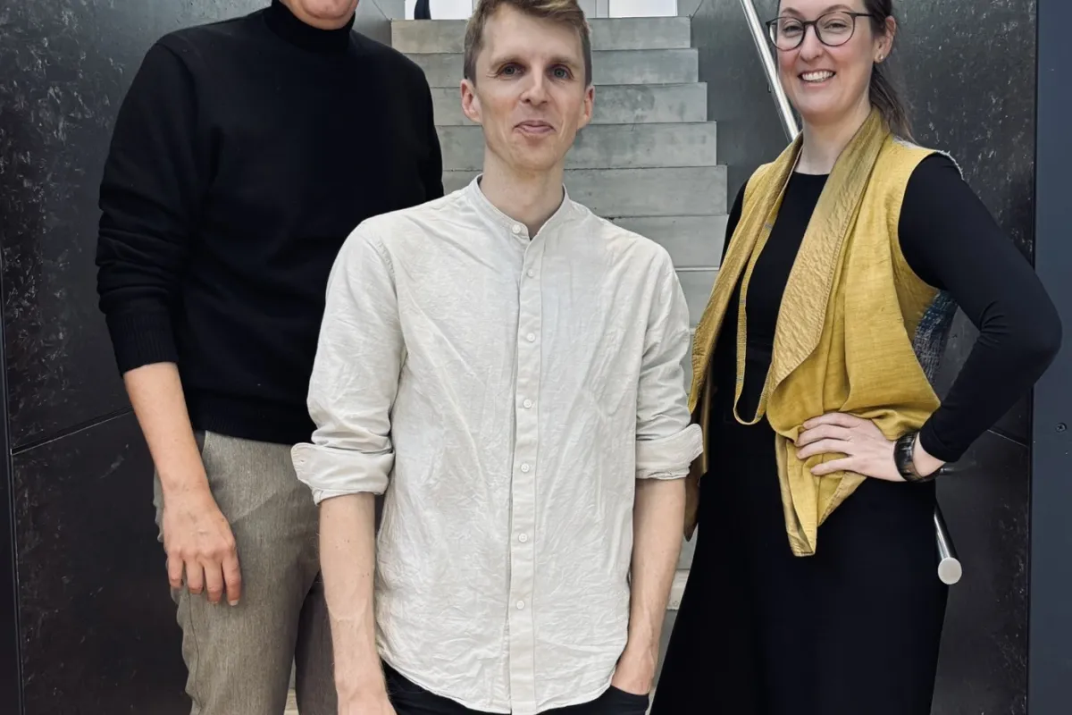 Drei Personen auf einer grau/schwarzen Treppe