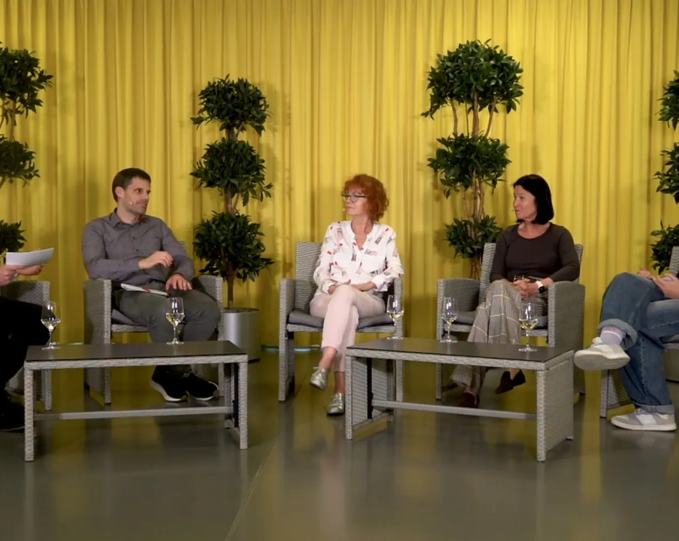 Podiumsdiskussion an der Universität Liechtenstein: Fünf Personen sitzen in einem Studio mit gelbem Vorhang und Pflanzen im Hintergrund. Sie diskutieren über Medienvielfalt und künstliche Intelligenz.