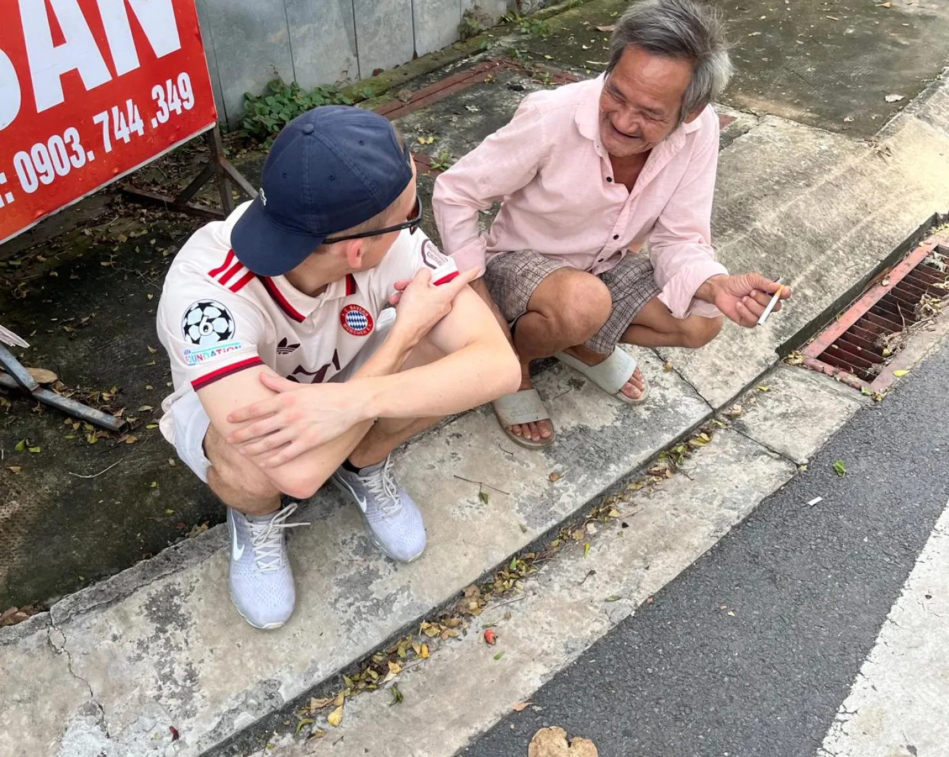 Der Autor zusammen mit einem Vietnamesen am Strassenrand sitzend