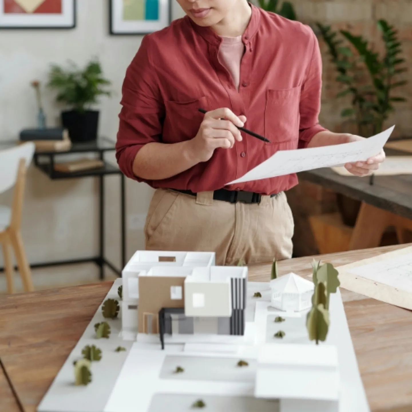 Eine junge Frau steht vor einem Tisch. Darauf steht ein Model eines kleinen Hauses.