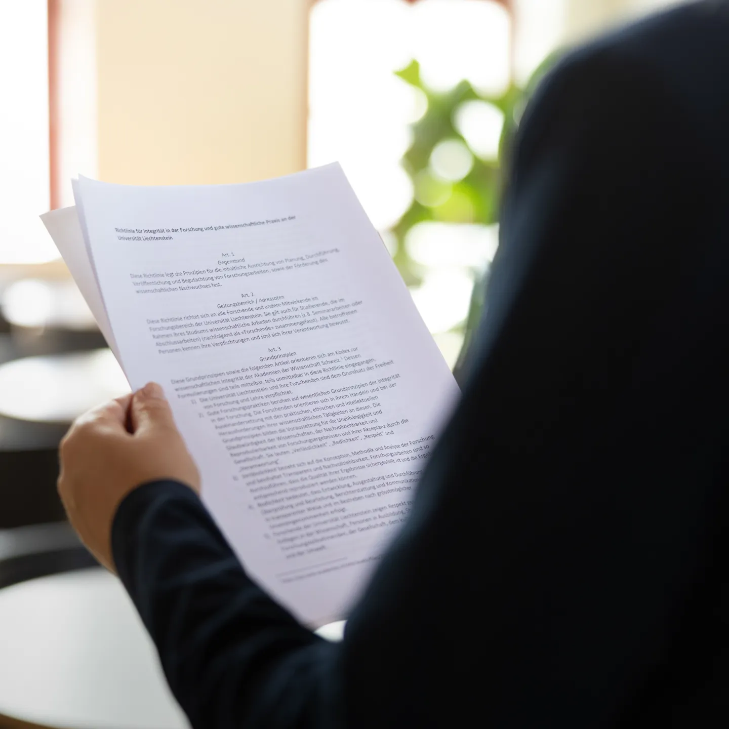Person hält ausgedruckte Dokumente mit wissenschaftlichem Text.
