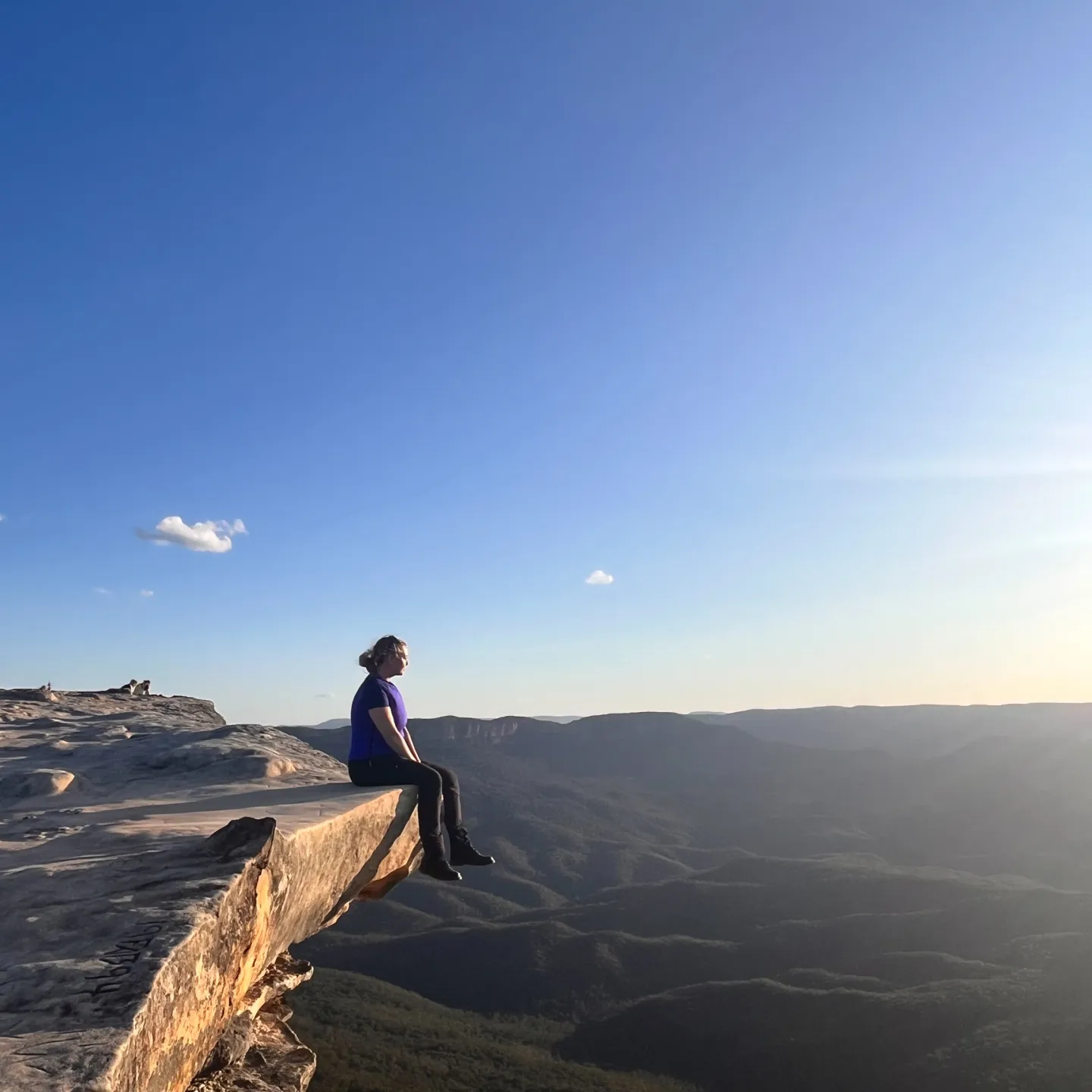 Eine Studierende der Universität Liechtenstein sitzt während ihres Auslandsaufenthalts auf einem Fels über einer Schlucht