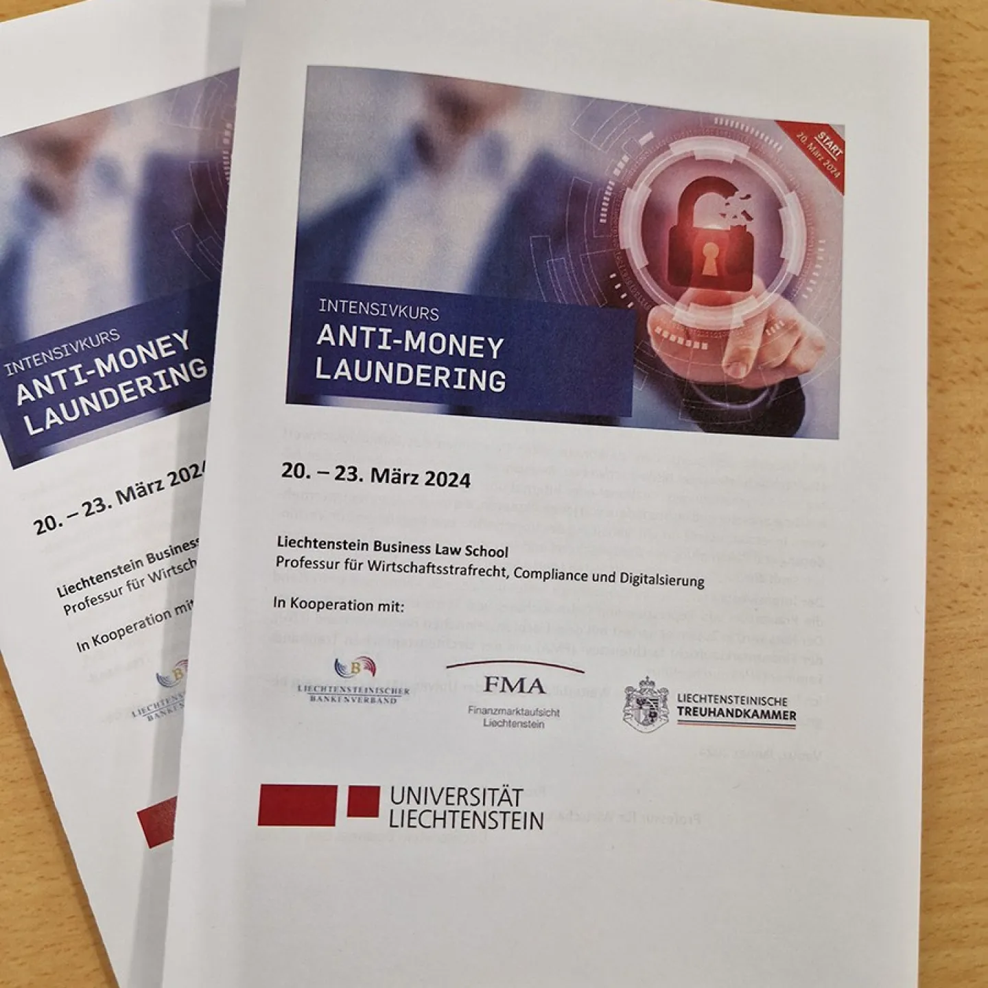 Broschüren des Intensivkurses „Anti-Money Laundering“ der Universität Liechtenstein, datiert auf 20.–23. März 2024, mit Logos von Kooperationspartnern und einem digitalen Schloss-Symbol auf dem Cover.