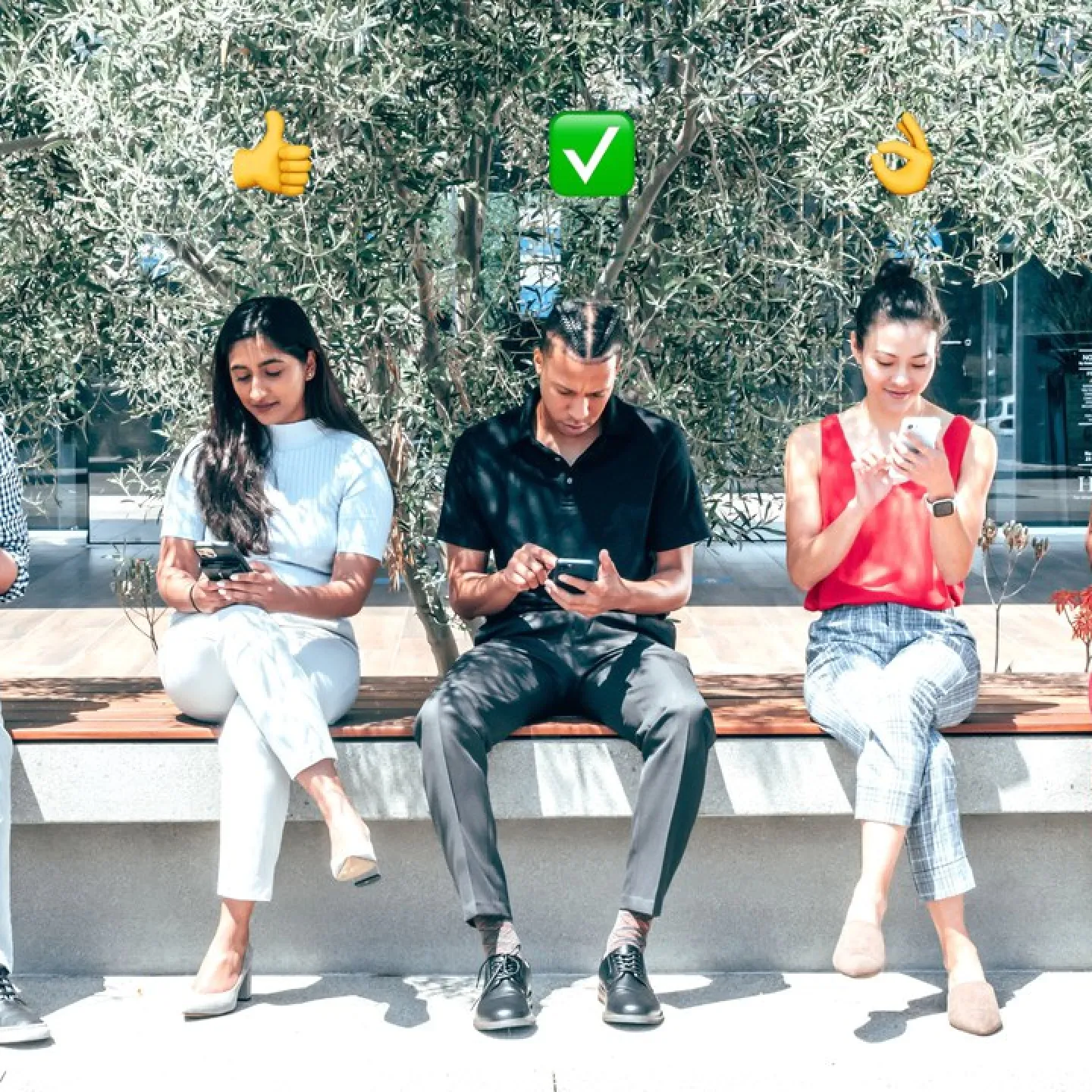Fünf Personen sitzen auf einer Bank im Freien und schauen auf ihre Smartphones. Über ihren Köpfen sind verschiedene Emojis zu sehen, die Emotionen und Gesten darstellen. Im Hintergrund sind Bäume und ein Gebäude sichtbar.