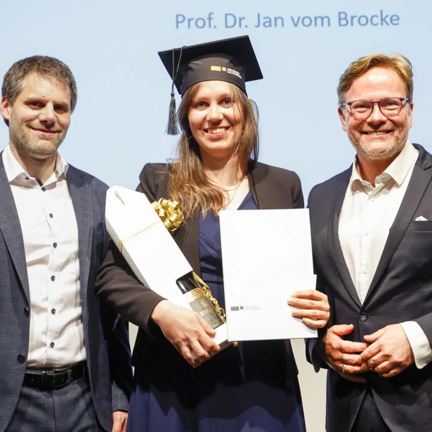 Dr. Christian Frommelt und Prof. Dr. Jan vom Brocke neben Dr. Amandine Herbé mit ihrem Diplom.