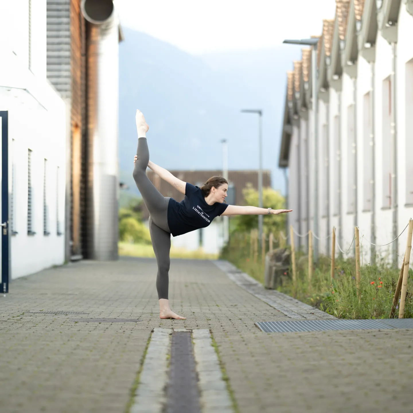Frau in Yoga-Pose auf dem Campus der Universität Liechtenstein im Freien.