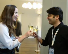 Zwei Teilnehmende der Universität Liechtenstein stoßen mit Weingläsern an bei einer Alumni Veranstaltung