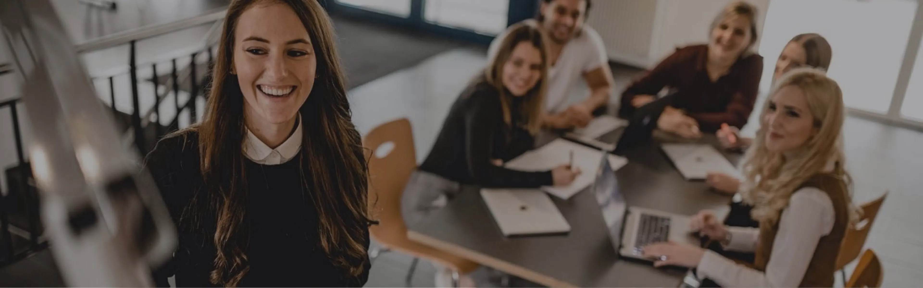 Eine Gruppe von Personen sitzt um einen Tisch herum und arbeitet mit Laptops.