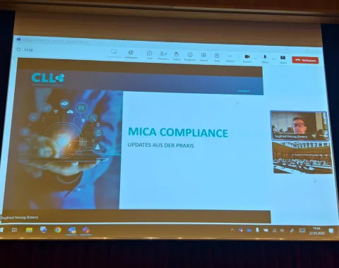 Präsentation auf einer Leinwand mit dem Titel "MICA Compliance: Updates aus der Praxis" beim Compliance-Day 2025 an der Universität Liechtenstein. Links ist ein Bild mit digitalen Symbolen, rechts ein kleines Videofenster mit einem Sprecher.