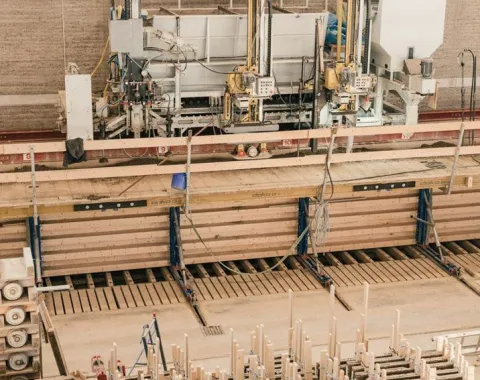 Produktionshalle für Lehmbau mit Maschinen und Holzstrukturen, die den Bauprozess veranschaulichen.