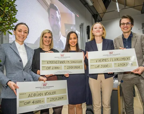 Fünf Studierende der Universität Liechtenstein halten große Schecks als Gewinner des I&F Family Wealth Preservation Awards. Im Hintergrund ist eine Person auf einem Bildschirm zu sehen.