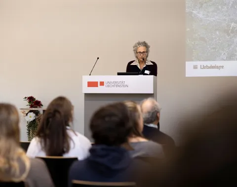 Frau mit Brille und Mikrofon bei einem Vortrag