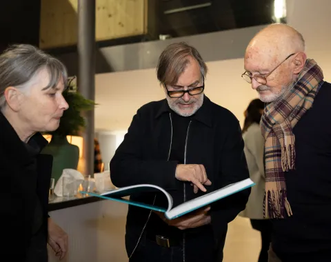 Drei Personen schauen auf ein Buch 