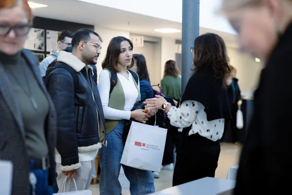 Studierende im Gespräch mit einer Mitarbeiterin der Universität Liechtenstein bei einer Veranstaltung im Eingangsbereich