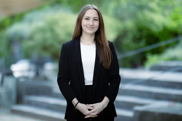 Studentin Bachelor BWL der Universität Liechtenstein im schwarzen Jacket lächelt in die Kamera – Campusaufnahme 