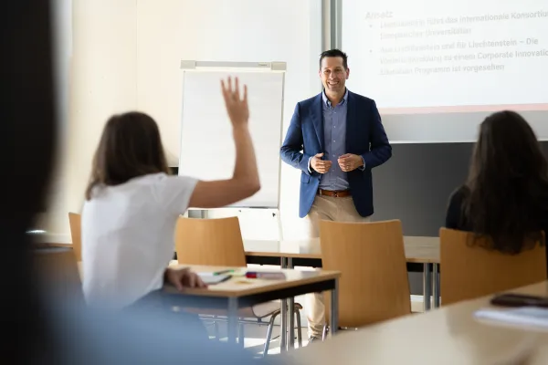 Dozent beantwortet eine Frage während einer interaktiven Lehrveranstaltung mit motivierten Studierenden.