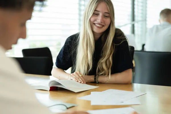 Studierende beim gemeinsamen Lernen in der Bibliothek der Universität Liechtenstein, Fokus auf Gruppenarbeit und Austausch.