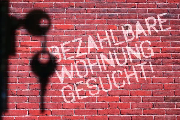 Mauer mit dem Schriftzug bezahlbare Wohnung gesucht
