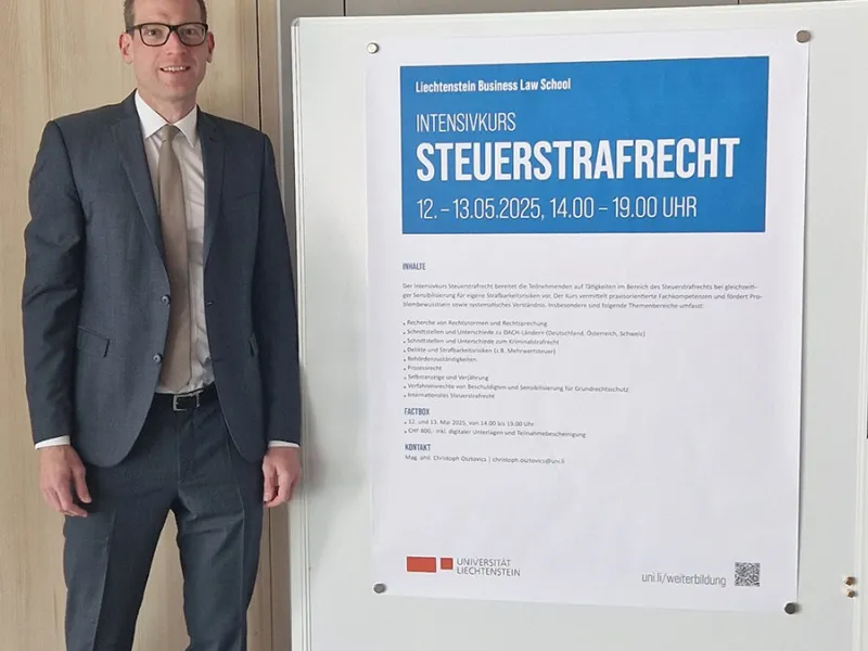 Ein Mann in Anzug steht neben einem Plakat, das den Intensivkurs „Steuerstrafrecht“ der Universität Liechtenstein ankündigt. Das Plakat enthält Informationen zu Datum, Uhrzeit und Inhalten des Kurses.